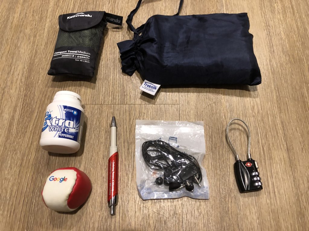 Miscellaneous gear, including microfiber towel, silk liner, gum, google hacky sack, pen, headphones and lock.